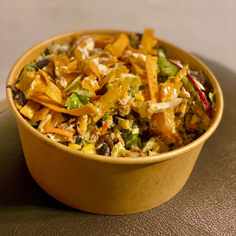A healthy Incred-A-Bowl Food Co. bowl filled with colorful ingredients and crispy tortilla strips.