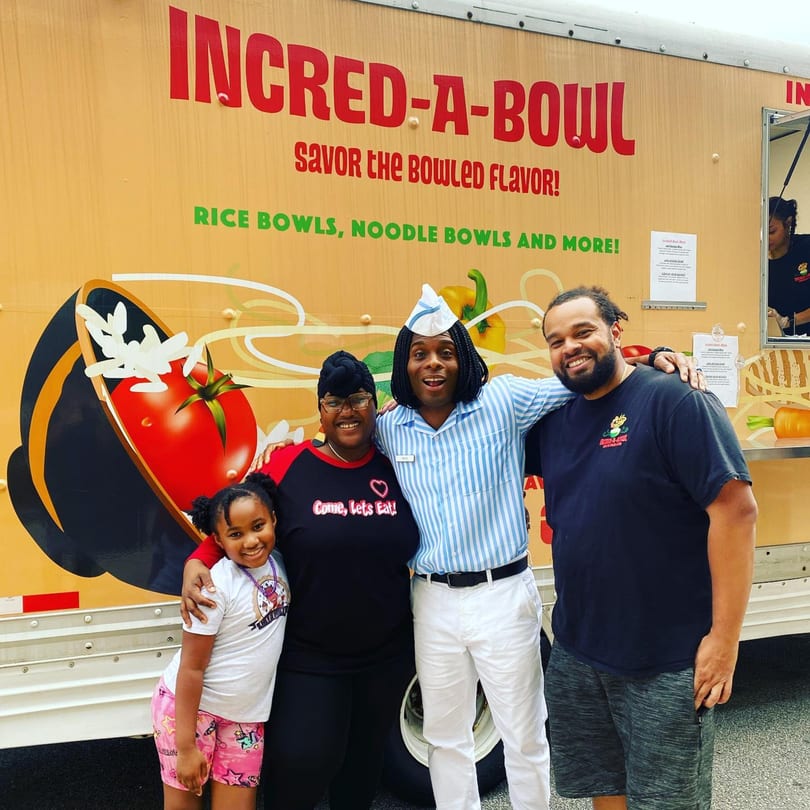 Four smiling people pose in front of the Incred-A-Bowl Food Co. food truck.
