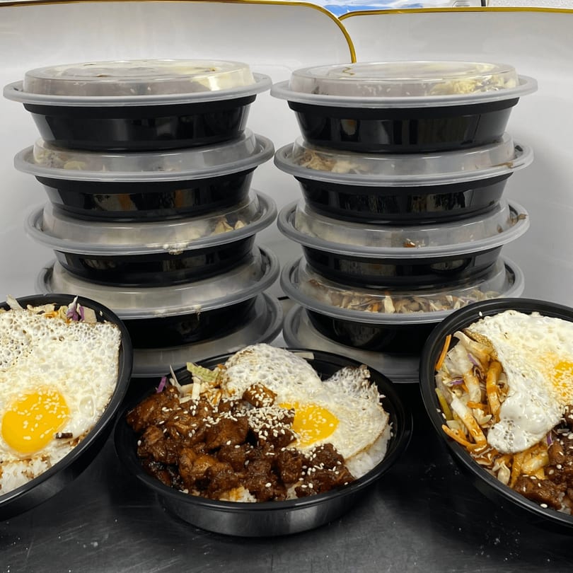 Three Incred-A-Bowl Food Co. healthy bowls with fried eggs, meat, and vegetables, with stacked to-go containers behind.