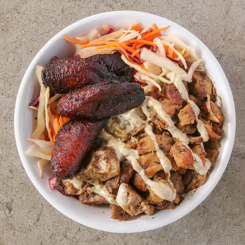 Incred-A-Bowl Food Co's healthy bowl with chicken, plantains, and coleslaw, drizzled with sauce.